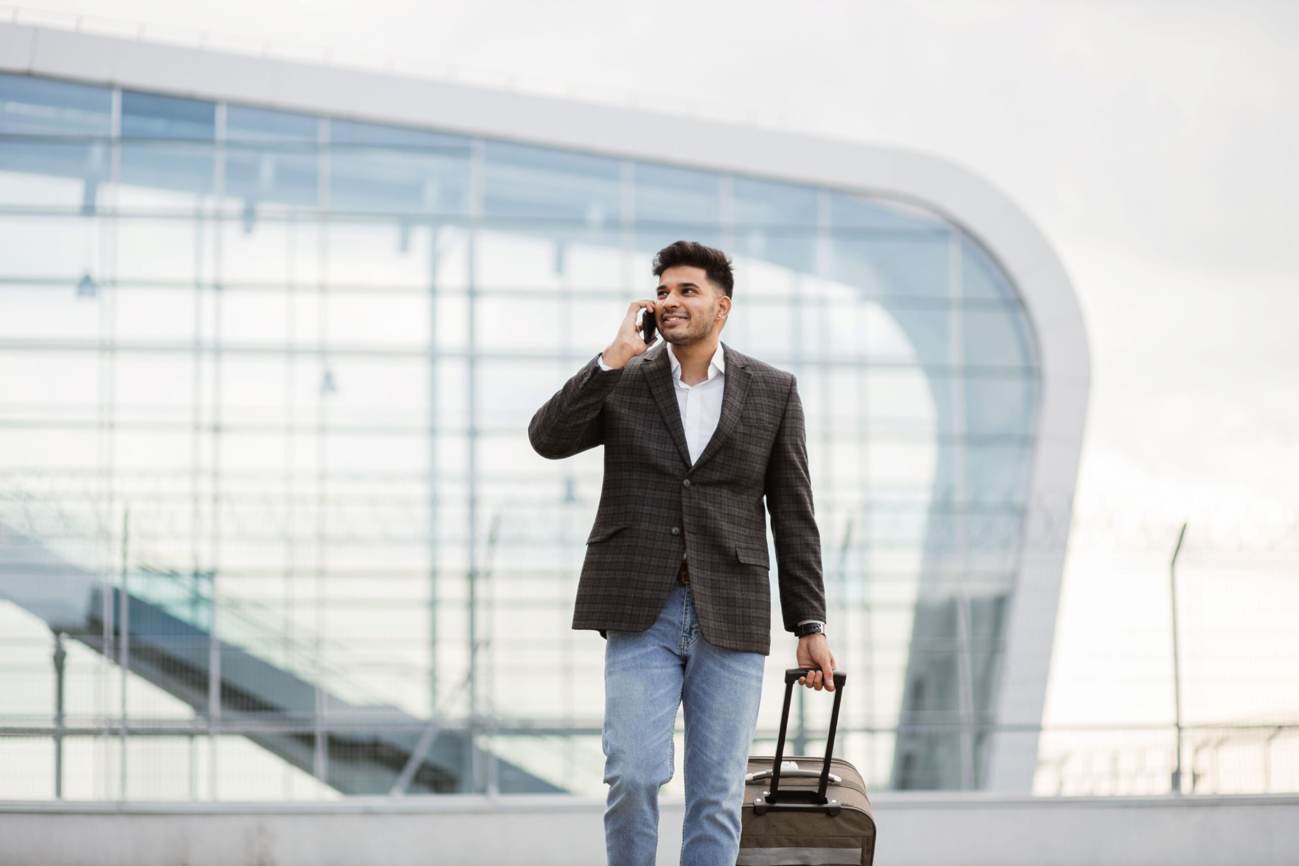 Person walking while on a phone call and holding a suitcase after they arrive in Canada.