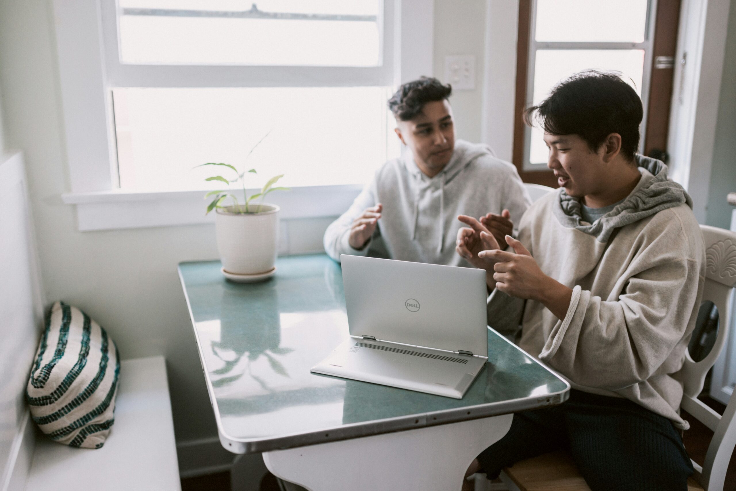 Two individuals discussing their financial situation at a table in front of a computer.