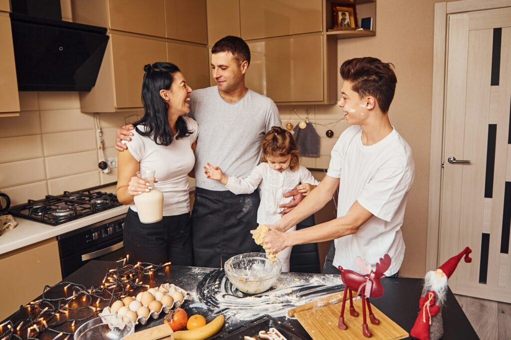 A mother and father in the kitchen with their two children preparing food