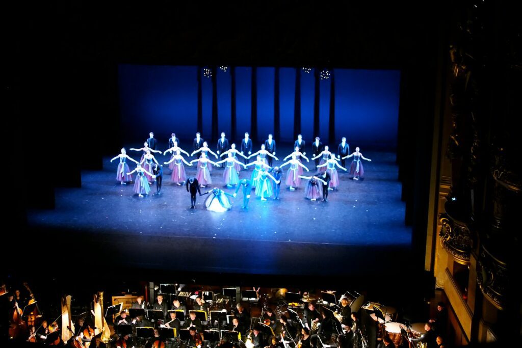 Ballet dancers on stage at the end of a show with the orchestra playing below the stage