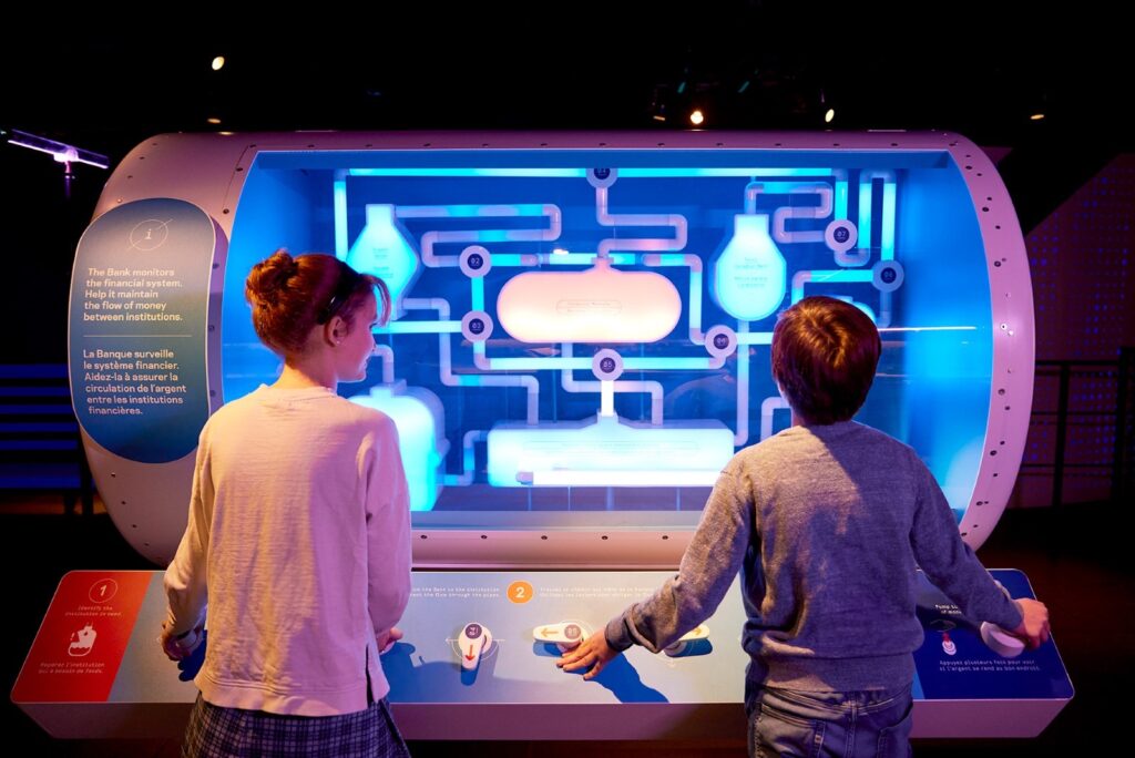 An image of two children playing with an interactive exhibit at the Bank of Canada Museum.