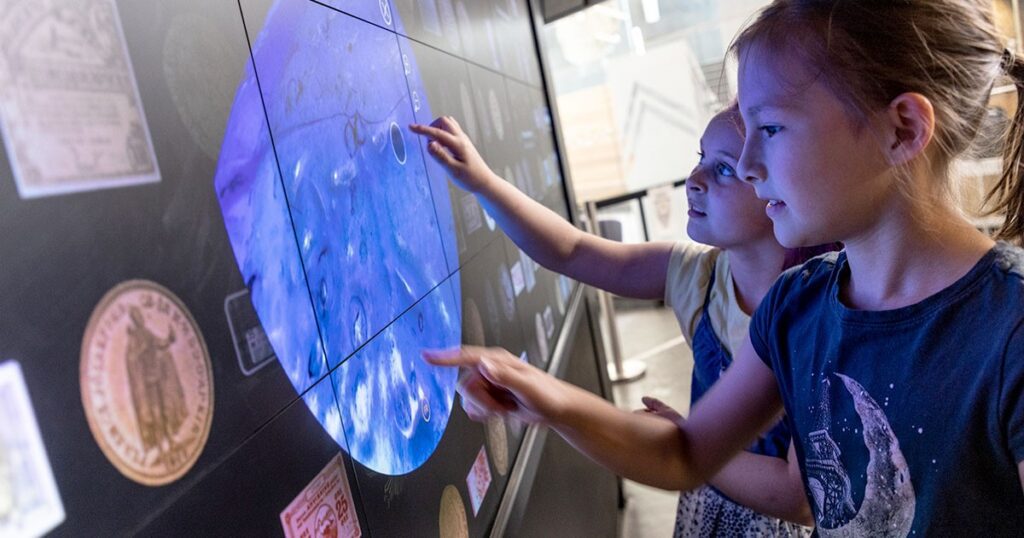 An image of two children playing with an interactive exhibit at the Bank of Canada Museum.